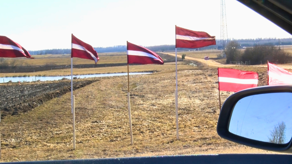 Ar Latvijas valsts karogiem vērš uzmanību ceļa stāvoklim